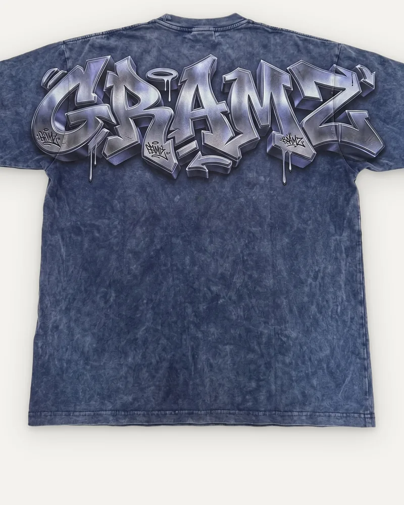 Design rendering: close-up of the chrome graffiti-style GRAMZ print across the back shoulders of the washed indigo tee