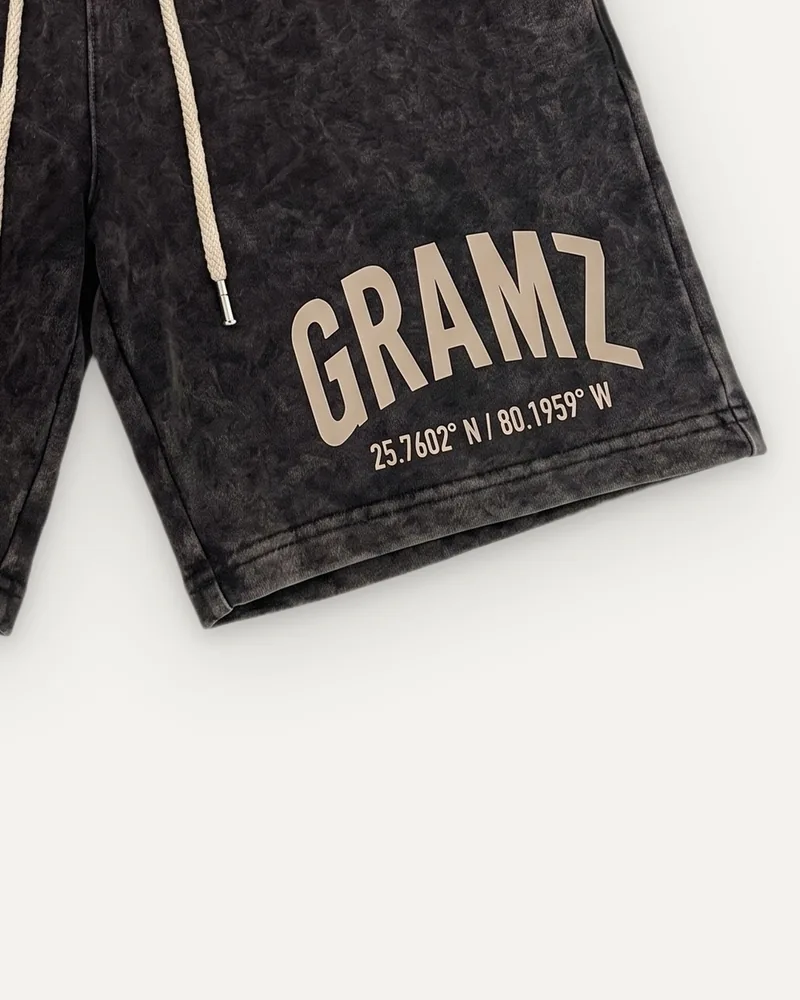 Design rendering: close-up of the sand arched GRAMZ print and Miami coordinates on the left leg of the washed charcoal sweat shorts