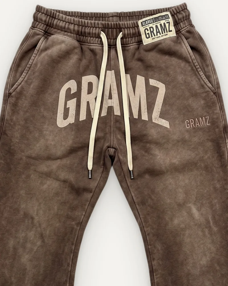 Design rendering: close-up of the sand arched GRAMZ print, cream drawcord and woven waistband label on the washed brown flared sweatpants