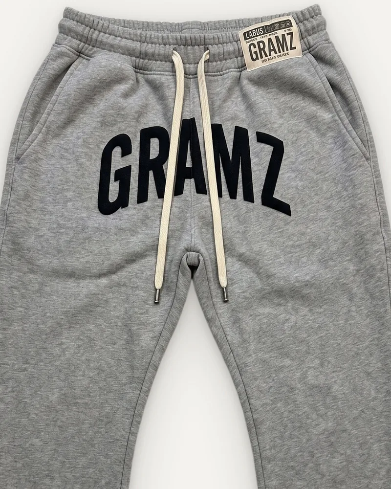 Design rendering: close-up of the black arched GRAMZ print, cream drawcord and woven waistband label on the heather grey flared sweatpants