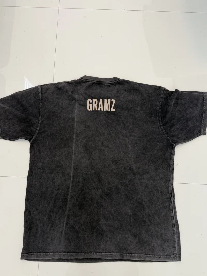 Back of the washed charcoal GRAMZ Arch Tee laid flat, with a small GRAMZ print below the collar