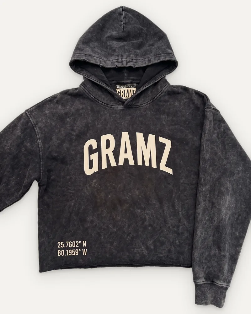 Design rendering: washed charcoal cropped hoodie with a sand arched GRAMZ chest print and Miami coordinates at the hem